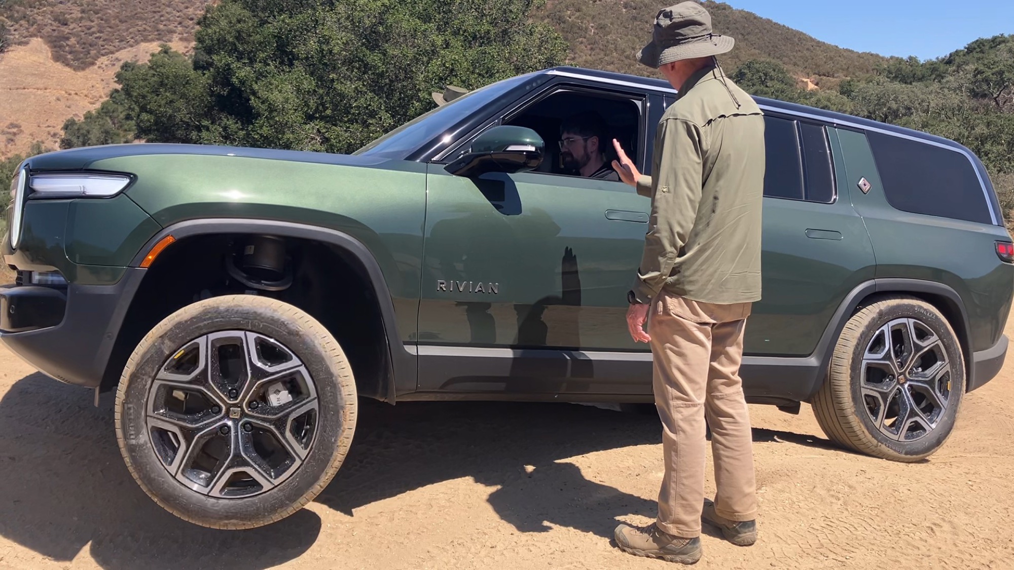 An instructor giving hand signals while coaching from outside the driver’s window