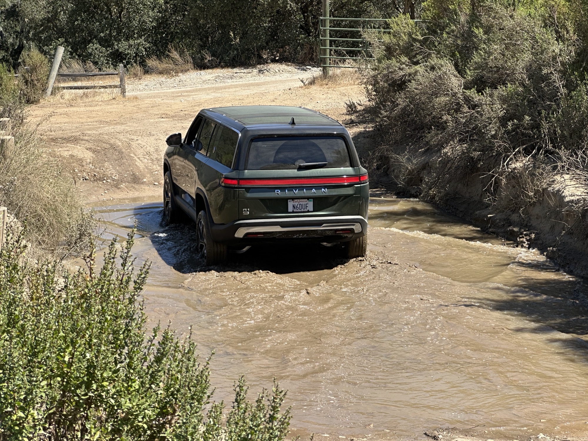 Rivian R1S crossing a muddy water crossing on the trail