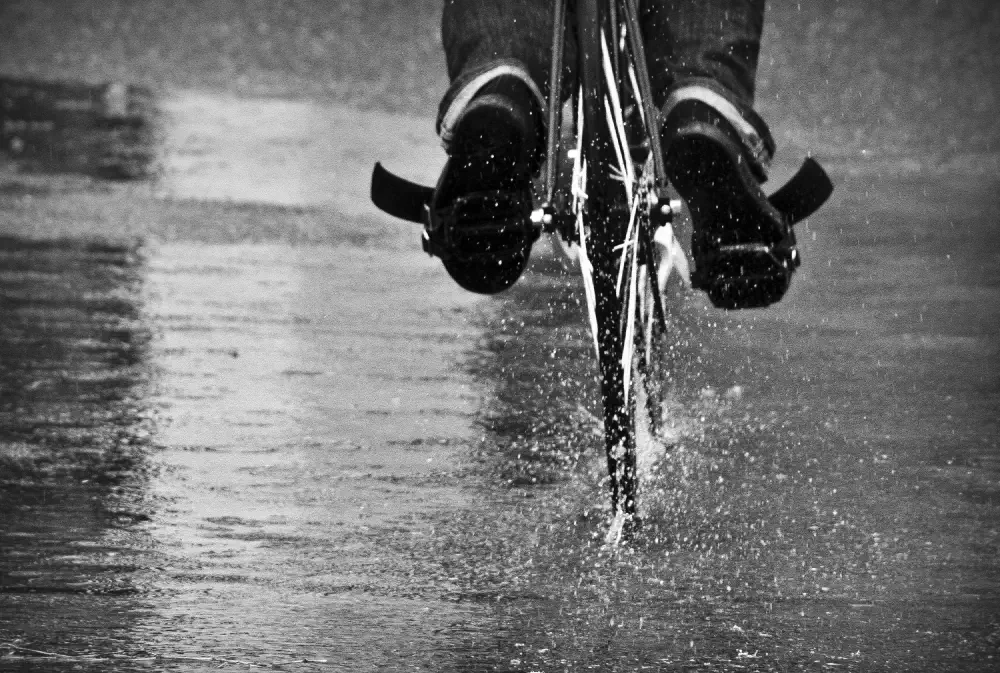 Black and white photo of a bike riding through a puddle and splashing water